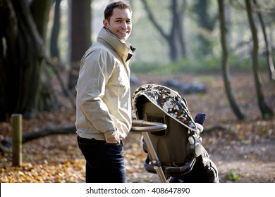 A Young Father Pushing A Stroller In The Park