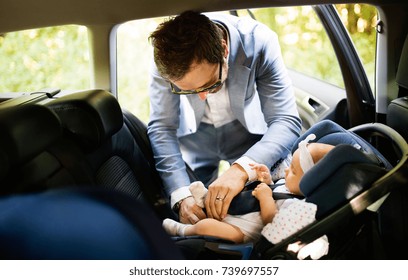 Young Father Putting Baby Girl In The Car.