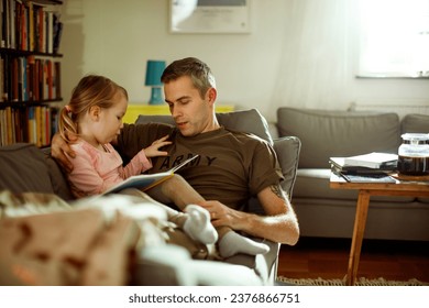 Young father reading with his daughter on the couch after coming back from the army at home - Powered by Shutterstock