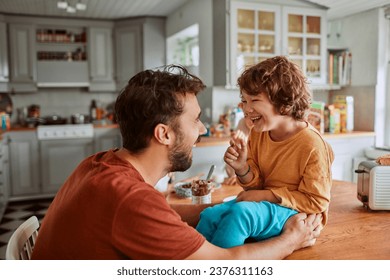 Young father and son being messy with chocolate spread in the kitchen at home - Powered by Shutterstock