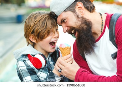 Young Father And Son Enjoying Icecream And Having Fun Together. Happy Emotional Family Outdoors. Vacation, Summer Time, Walking At City. Father Playfully Tries To Eat Icecream.