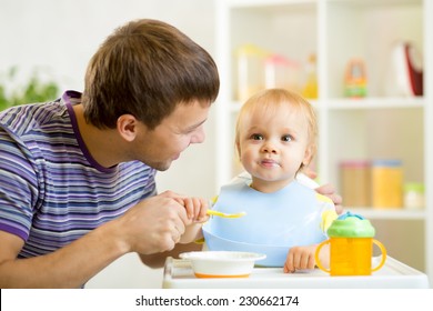 Young Father Teaching Baby Kid Son To Eat With Spoon