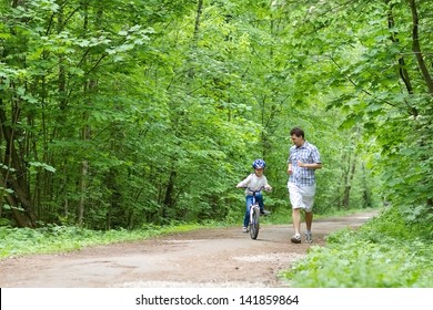 Young Father Teaching His Son To Ride A Bike