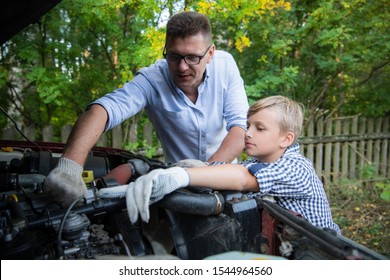 Young father teaching his son to change motor oil in family car.