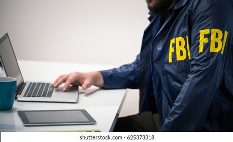 Young FBI agent in uniform in office using laptop
