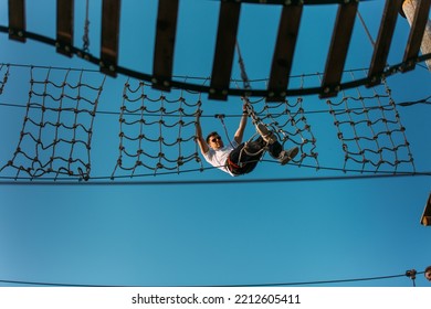 Young Fearless Man Going Through The Net Wall With Ease In The Adventure Park