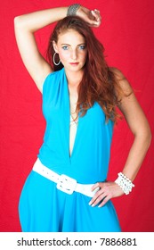 Young Female Adult Fashion Model With Natural Red Hair And Freckles In A Blue Summers Dress With White Belt (red Textured Faux Leather Background)