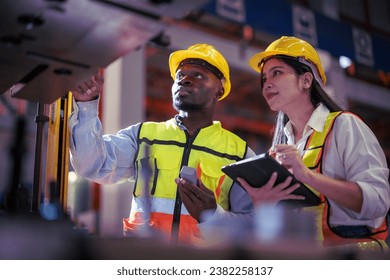 Young female and african american male workers in a factory for the production of metal sheet factory. Inspecter factory worker holding clipboard checking quality of machine. - Powered by Shutterstock