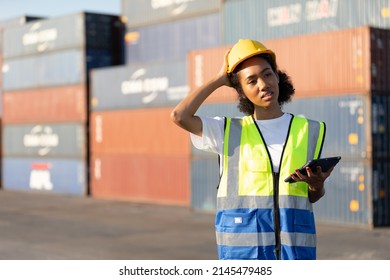 Young Female African Factory Worker Or Engineer Holding Tablet Computer And Thinking About Work In Containers Warehouse Storage