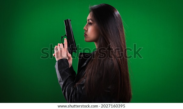 Young female agent with a gun in her hand -\
studio photography