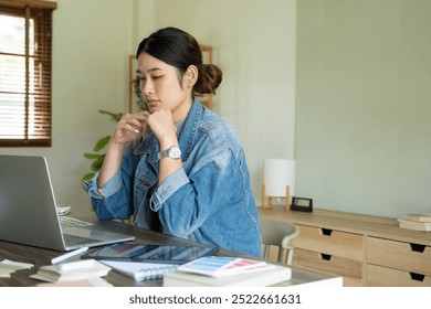 Young female architect or interior designer sits at her desk with equipments in the office, she works with laptop and brings her design ideas to life and selects colors from charts,  - Powered by Shutterstock