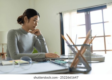 Young female architect or interior designer sits at her desk with equipments in the office, she works with laptop and brings her design ideas to life and selects colors from charts,  - Powered by Shutterstock