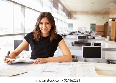 Young Female Architect Working With Computer And Blueprints