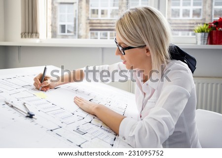 Young female architect working on blueprint