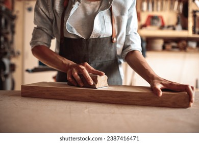 Young Female Artisan Carpenter Sanding Wood in a Workshop - Powered by Shutterstock