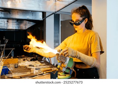 A young female artisan expertly shapes molten glass with flames, showcasing her craftsmanship amidst an artisan workshop environment. - Powered by Shutterstock