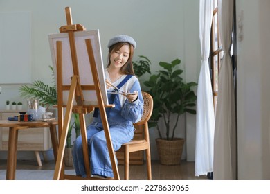 Young female artist mix color on palette to painting artwork on canvas with enjoying in home studio. - Powered by Shutterstock