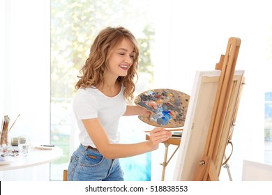 Young Female Artist Painting Picture In Studio