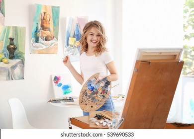 Young Female Artist Painting Picture In Studio