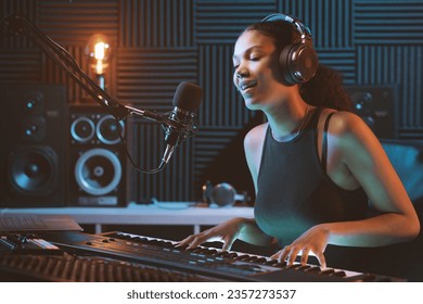 Young female artist recording a song in the studio, she is singing and playing the keyboard - Powered by Shutterstock