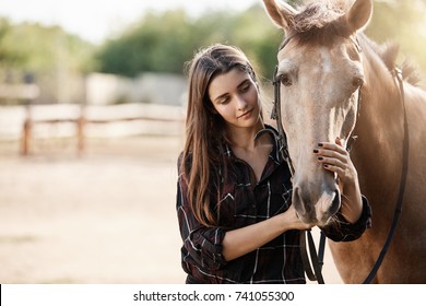 Young female assistant farm manager caring about a horse. - Powered by Shutterstock