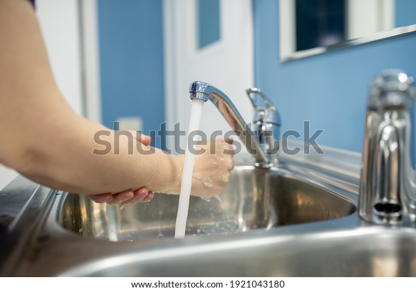 Young female assistant, nurse or surgeon washing\
hands over one of two metallic sinks before or after medical\
procedure in hospital