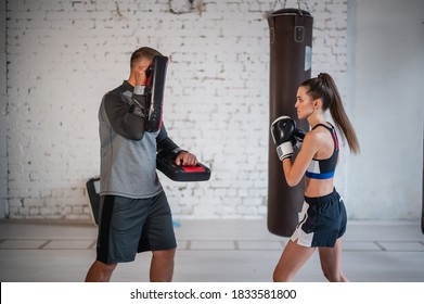 A Young Female Athlete In Good Physical Shape Conducts Kickboxing Training Under The Supervision Of An Experienced Male Coach