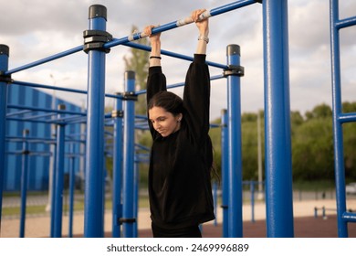 Young Female Athlete Hanging on the Bar on Outdoor Exercise Equipment - Powered by Shutterstock