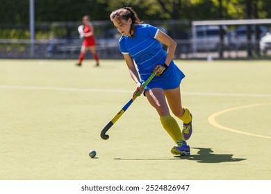 Young female athlete playing field hockey on a sunny day. - Powered by Shutterstock