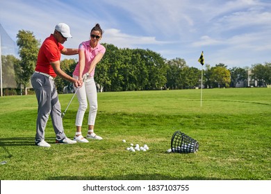Young female athlete practicing a golf swing on the course helped by a skilled instructor