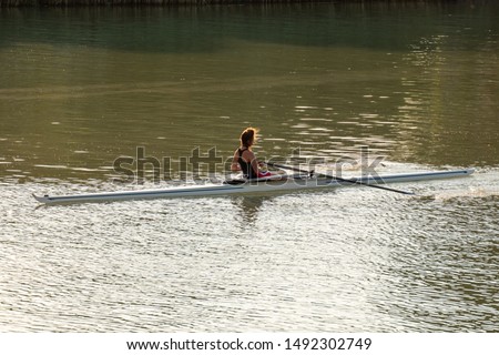 A young female athlete is rowing in a single scull on the Danube, Budapest Hungary