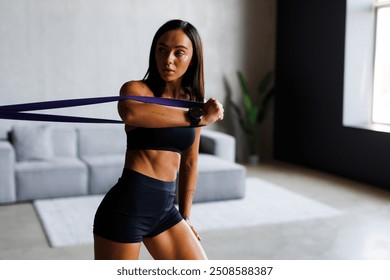 Young female athlete using resistance band while working out in the living room. - Powered by Shutterstock