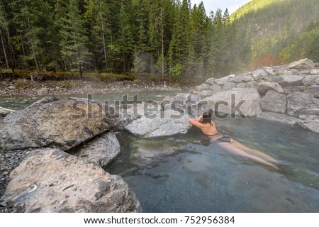 A young female in a bikini laying in the natural hot springs next to Lussier River in Whiteswan Provincial Park, British Columbia, Canada