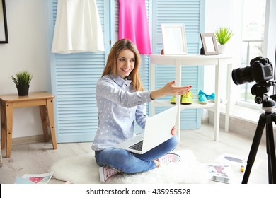 Young female blogger with laptop recording video at home