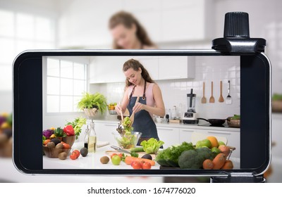 Young Female Blogger And Vlogger And Online Influencer Live Streaming A Cooking Show On Social Media Using A Smartphone