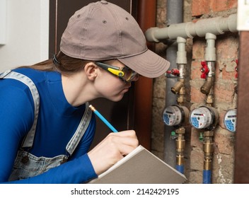 Young Female Blue Collar Manual Labour Worker Wearing Protective Glasses Writes Meter Counter Readings