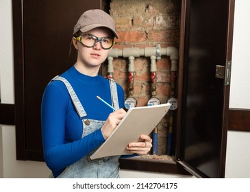 Young Female Blue Collar Manual Labour Worker Wearing Protective Glasses Writes Meter Counter Readings