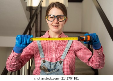 Young Female Blue Collar Manual Labour Worker Shows Tape Measure