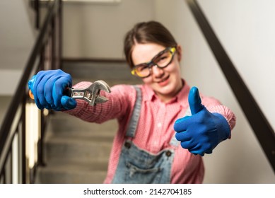 Young Female Blue Collar Manual Labour Worker Holds Wrench And Shows Thumbs Up