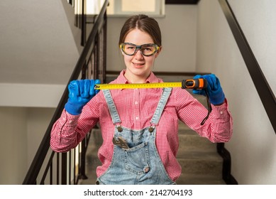 Young Female Blue Collar Manual Labour Worker Shows Tape Measure