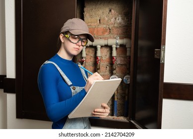 Young Female Blue Collar Manual Labour Worker Wearing Protective Glasses Writes Meter Counter Readings