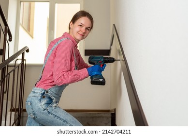 Young Female Blue Collar Manual Labour Worker Holds Cordless Screwdriver At Construction Site