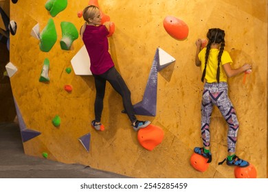 Young female bouldering instructor helping boy climb artificial wall - Powered by Shutterstock