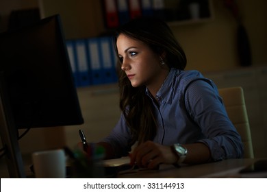 Young Female Business Woman Working At Home.She Works Late Into The Night Looking At Monitor.