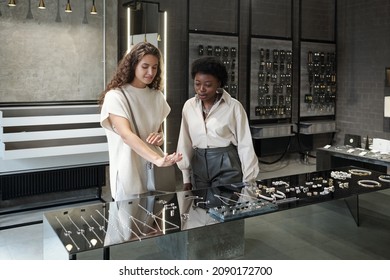 Young female buyer consulting with shop assistant while trying on new ring in large contemporary jewelry boutique - Powered by Shutterstock