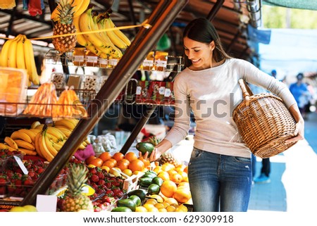 Young female buys fruits on street market.