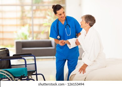 young female caregiver helping senior woman getting up