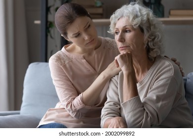Young female caregiver support grieving suffering mature old woman retiree express empathy compassion. Supportive grown up daughter hug mature mother help overcome loss of beloved man health problem - Shutterstock ID 2002099892