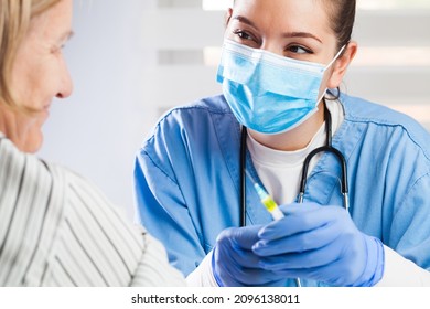 Young female caucasian medical NHS worker giving coronavirus injection shot to elderly woman patient,immunization against COVID-19 virus disease,booster dose for protection and creation of antibodies - Shutterstock ID 2096138011