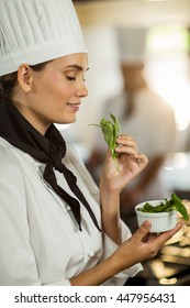 Young Female Chef Smelling Herb In Commercial Kitchen